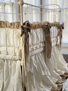 three cribs with ruffled bedspreads and bows hanging from the rails