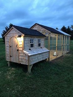 a chicken coop in the middle of a grassy field with a light on it's roof