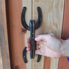 a person is holding onto a pair of black handles on a wooden door with wood planks in the background