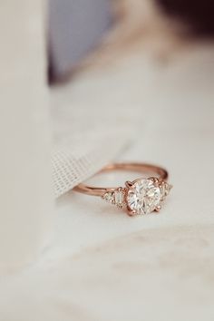 a diamond ring sitting on top of a white table next to a piece of cloth