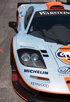 an orange and blue race car is parked on the street