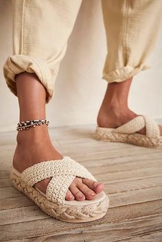 a pair of feet wearing crochet sandals on a wooden floor next to each other