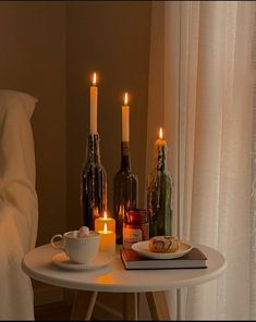 candles are lit on a table with food and wine bottles