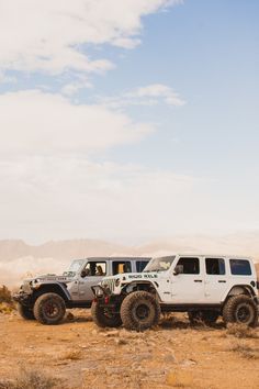 two white jeeps parked in the desert