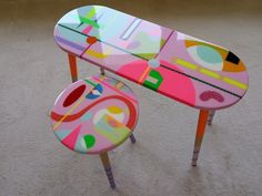 a colorful table and stool are on the floor