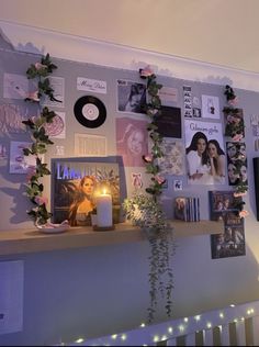 there is a wall with many pictures on it and a candle in front of it