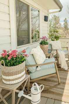 a porch with two chairs and flowers on the back deck, next to a potted plant