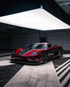 a red and black sports car parked in a garage