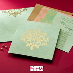 two wedding cards with gold and green designs on them next to each other in front of a red background