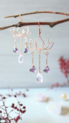 some kind of jewelry hanging from a tree branch with leaves and crystals on it's hooks