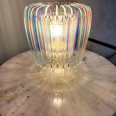 a multicolored glass lamp sitting on top of a marble table next to a chair