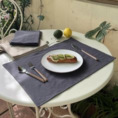 a hot dog with avocado on it sitting on a table next to silverware