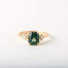 a green and white diamond ring on a white surface