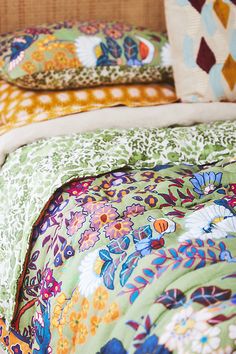 a bed with colorful sheets and pillows on top of it