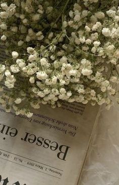a bunch of white flowers sitting on top of a newspaper with the word bead gut written in russian