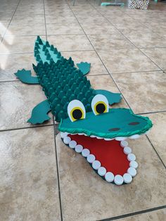 an alligator made out of legos sitting on the floor with it's mouth open