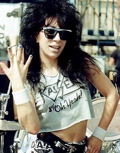 a woman with black hair and sunglasses holding her hand up