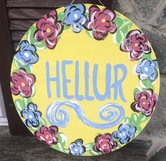 a painted sign that says,'hellor'with flowers on it hanging from the side of a building