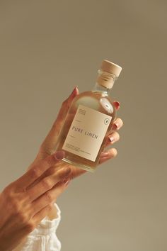 a woman holding up a bottle of pure linen