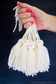 a hand holding three white tassels with ghost faces on them