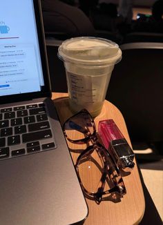 an open laptop computer sitting on top of a wooden table next to a cup of coffee