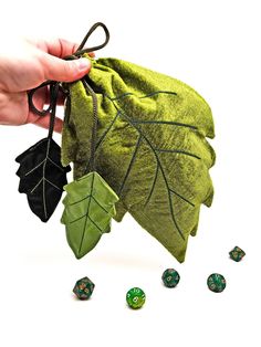 a hand holding a green bag with leaves and dices on the ground next to it