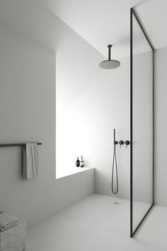 a white bathroom with a shower head, toilet and towel hanging on the wall next to it