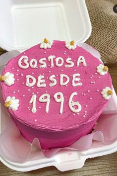 a pink cake with white frosting and flowers on it in a plastic container that says costasa desde 1910