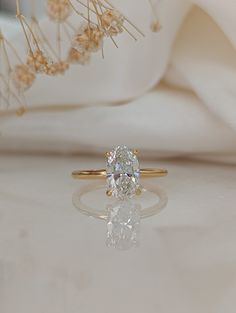 a diamond ring sitting on top of a white cloth next to some flowers and grass