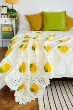 a crocheted blanket with lemons on it in front of a white bed