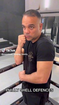 a man standing in front of a boxing ring with his fist up to his face