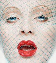 a woman with red lipstick and netting on her face