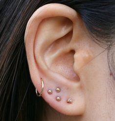 a close up of a person's ear with three piercings