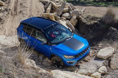 a blue jeep driving up a rocky hill