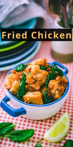 fried chicken in a blue and white bowl on a checkered tablecloth with lime wedges