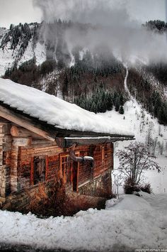 an old log cabin with snow on the roof