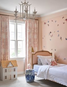 a bedroom decorated in pink and white with a doll house on the floor next to it