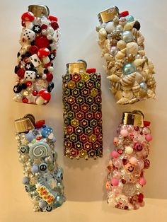 four cell phones are lined up on a white surface with beads and charms attached to them