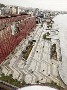 an aerial view of a red building next to the water with people walking around it