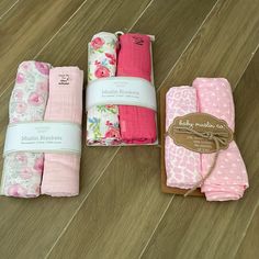 four folded pink and white cloths sitting on top of a wooden floor next to each other