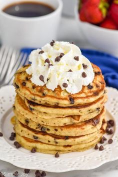 a stack of chocolate chip pancakes topped with whipped cream and chocolate chips on a white plate