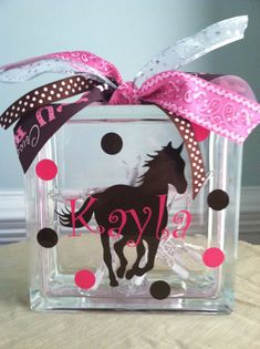 a glass block with a horse on it and polka dot ribbon around the top that says kyra