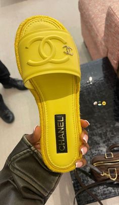 a person holding up a yellow chanel slipper