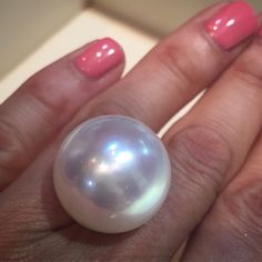 a woman's hand with a pink manicure and a pearl ring