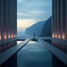 a person standing in the middle of a pool with mountains in the background at dusk