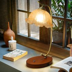 a lamp that is on top of a desk next to a book and some books