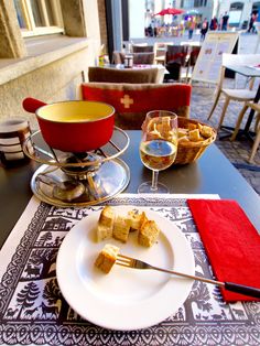 a white plate topped with food on top of a table next to a glass of wine