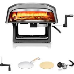 an electric pizza oven with the lid open and cooking tools next to it on a white background