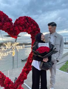 a man and woman standing next to a heart shaped arrangement