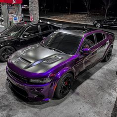 two purple and black cars are parked in a parking lot next to each other at night